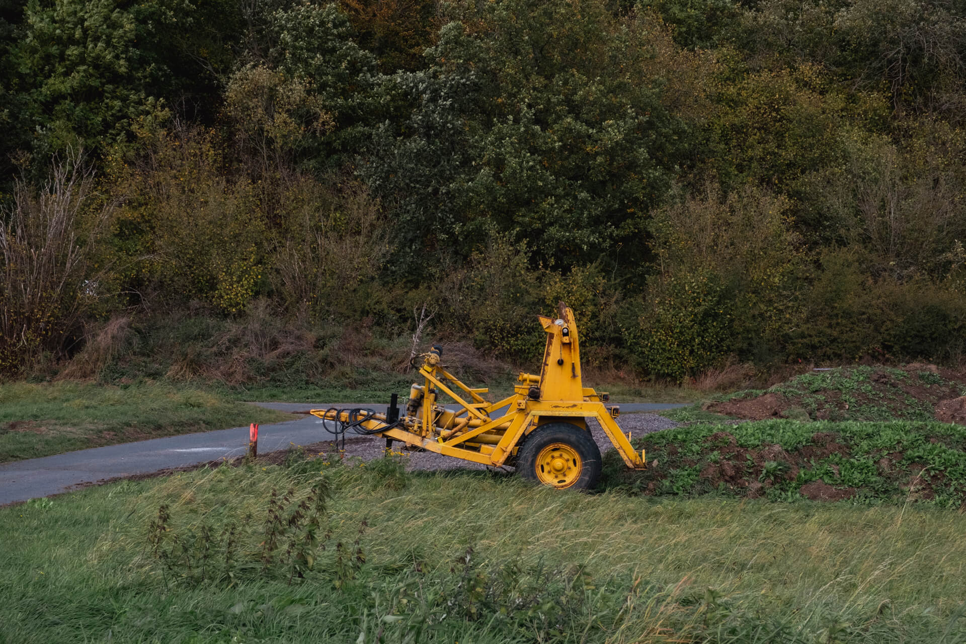 Gelber Anhänger für Kabeltrommeln auf einer Wiese.